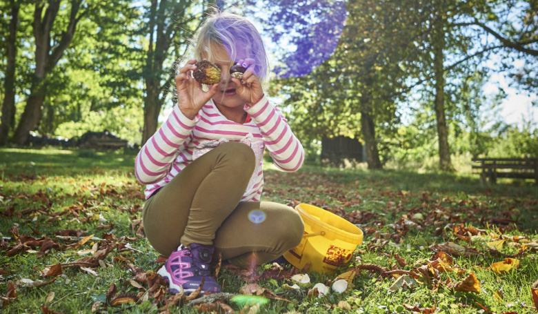 Der goldene Herbst in all seinen Farben und Formen - Kind sammelt Kastanien.