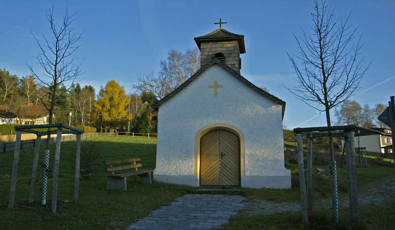 Kapelle in herbstlicher Landschaft.