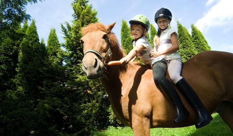 Zwei Mädchen reiten auf dem Pferd.