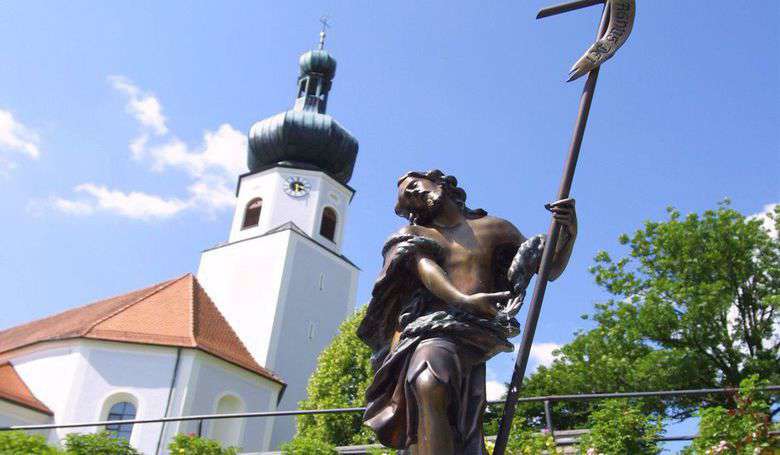 Moosbacher Kirche mit Bronzefigur im Vordergrund